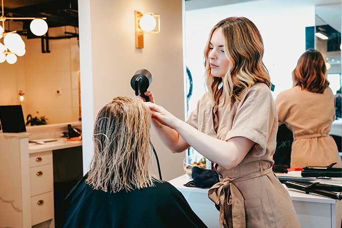 Frisør som føner hår. Foto.
