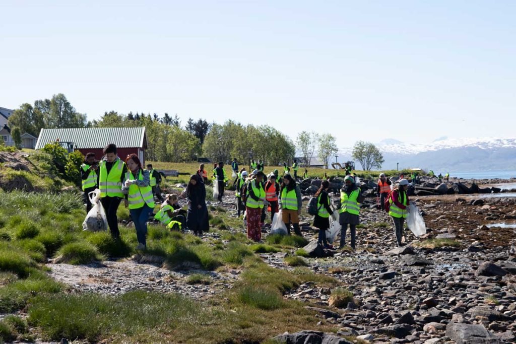 personer med søppelsekker i fjæra